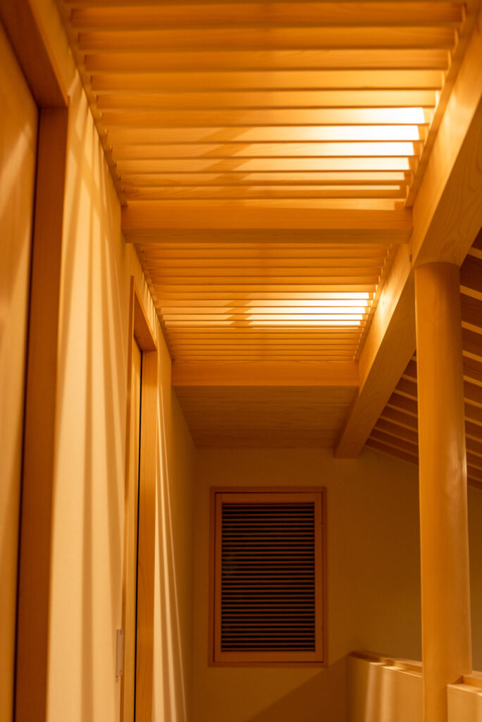 設計事務所による土間庭の家のヒノキの格子天井、照明点灯時